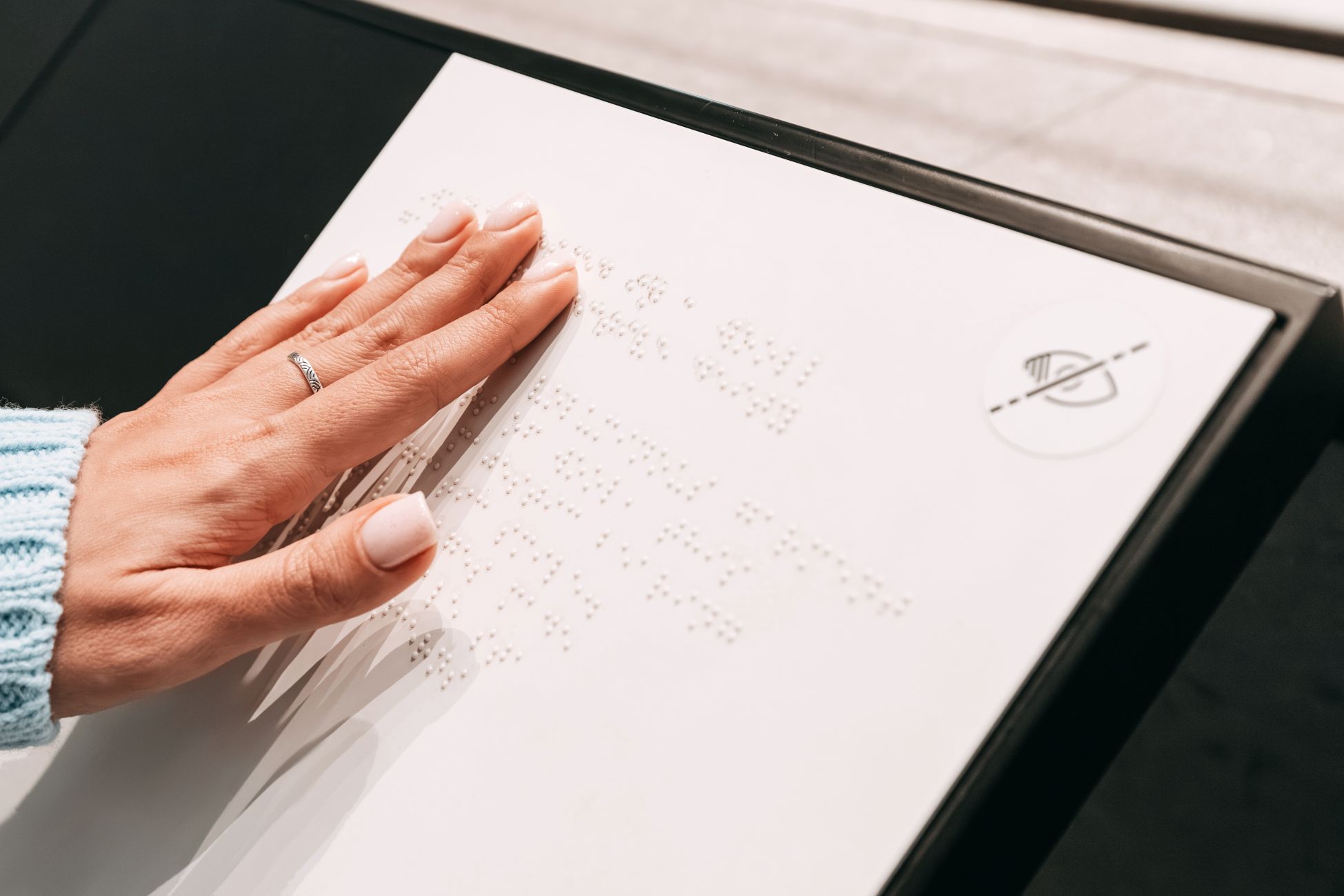 Closeup of woman's as she reads a braille inscription on a board at museum in United Arab Emirates.